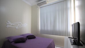 A bedroom with a bed, a TV, and a window with blinds. - Dutra 1104 (Rio de Janeiro)