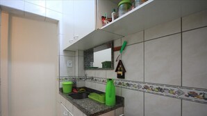 A compact kitchen with a granite countertop, a green dish rack, and a small window above the sink. - Dutra 1104 (Rio de Janeiro)