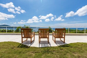 Three wooden chairs facing a scenic view of a body of water and a bridge. - Leisure LULU VILLA (Hengchun)