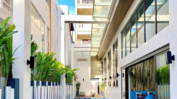 Een modern gebouw met een centraal gelegen zwembad, glazen balustrades en buiten zitplekken.