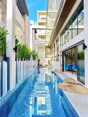 A modern building with a central swimming pool, glass railings, and outdoor seating areas.