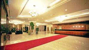 A spacious lobby with a red carpet, a reception desk, and a large potted plant. - Yaling Hotel (Magong)