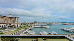 A marina with boats docked, a large hotel building, and a road with vehicles. - Yaling Hotel (Magong)