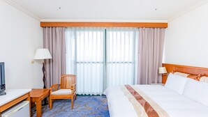 A hotel room with a bed, a desk, a chair, a TV, and a window with curtains. - Yaling Hotel (Magong)