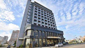 A tall, modern hotel with a prominent corner entrance and multiple floors. - Yaling Hotel (Magong)