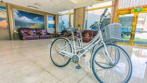 Un hall d’entrée avec un vélo blanc, des canapés en cuir et de grandes fenêtres.