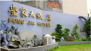 L’extérieur de l’hôtel FONG JIA se caractérise par une façade recouverte de carreaux, un mur en pierre avec des rochers et un petit appareil de climatisation.