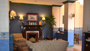 A traditional living room with a fireplace, patterned sofas, and a bookshelf. - Hotel Isla Rey Jorge (Punta Arenas)