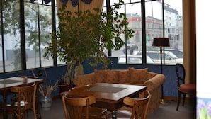 A room with a large window, a sofa, a dining table, and chairs. - Hotel Isla Rey Jorge (Punta Arenas)