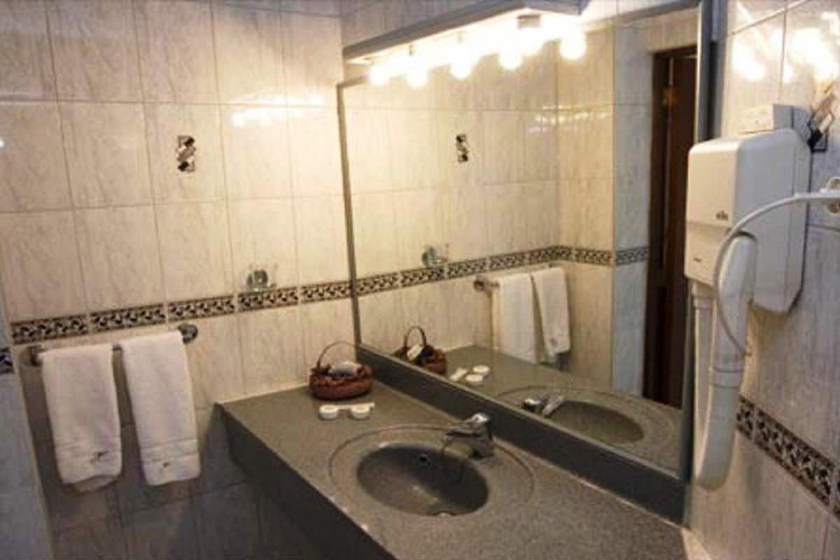 A bathroom with a large mirror, two sinks, and a towel rack.