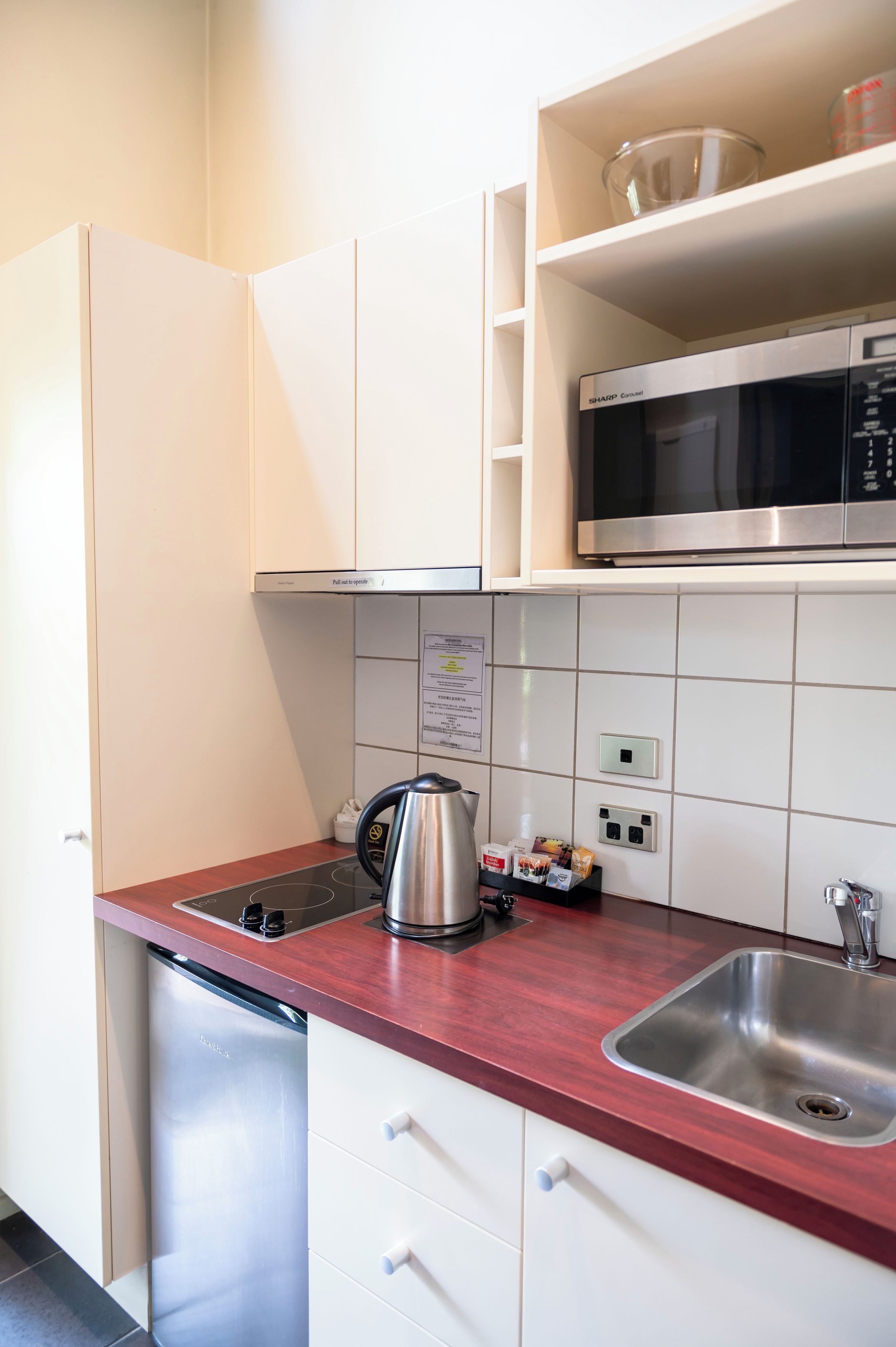 Una cocina compacta con microondas, hervidor y lavavajillas.