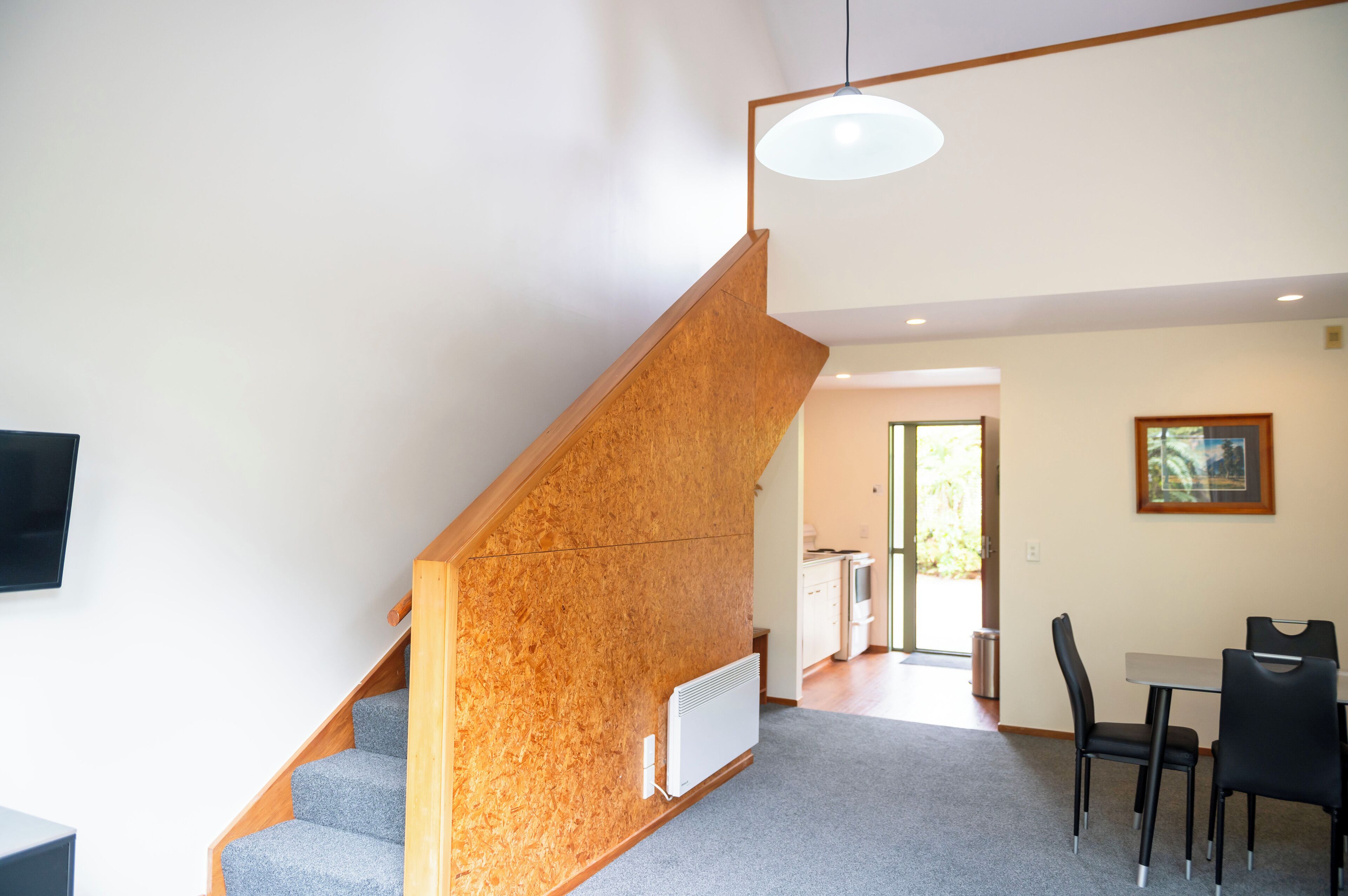 Un interior moderno con escalera de madera, comedor y cocina.
