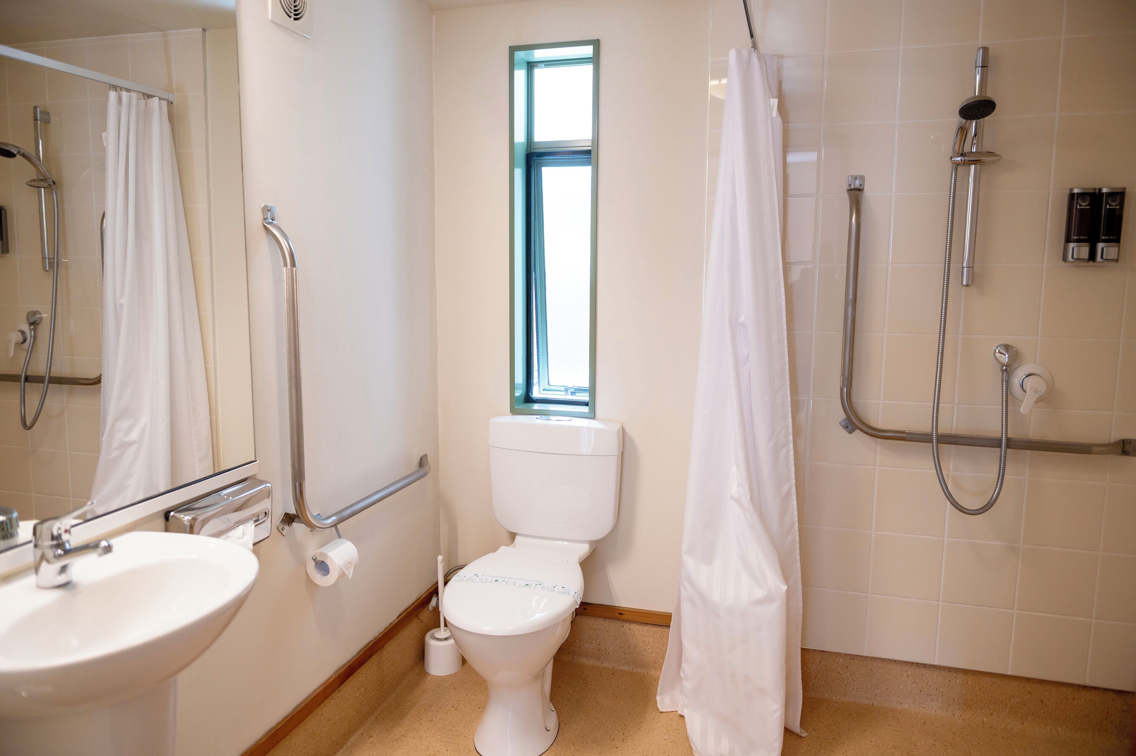 Une salle de bain avec des toilettes, un lavabo, une douche et une fenêtre.