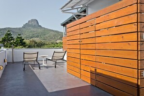 A rooftop terrace with a view of a mountain, wooden paneling, two chairs, and a small table. - Apple Room Hostel (Hengchun)