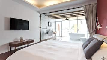 Un dormitorio moderno con una cama grande, un televisor de pantalla plana, una mesita de noche con un modelo de barco y vistas al baño y al exterior.