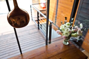A wooden staircase with a metal railing, a hanging pendant light, and a vase with flowers on a wooden table. - Apple Room Hostel (Hengchun)