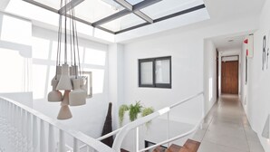 Un interno moderno con soffitto in vetro, pareti bianche e una scala in legno.