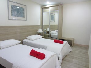 A hotel room with two single beds, a large mirror, a bedside table with a lamp, and a bench. - Naam Boutique Lodge (Port Dickson)