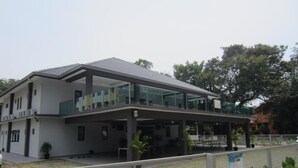 A modern two-story building with a flat roof, large glass windows, and a covered outdoor area. - Naam Boutique Lodge (Port Dickson)