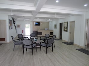A conference room with a round table, chairs, a television, and a reception desk. - Naam Boutique Lodge (Port Dickson)
