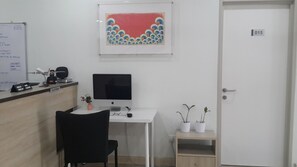 Zona de recepción con escritorio, computadora, silla y una puerta identificada con el número 015.
