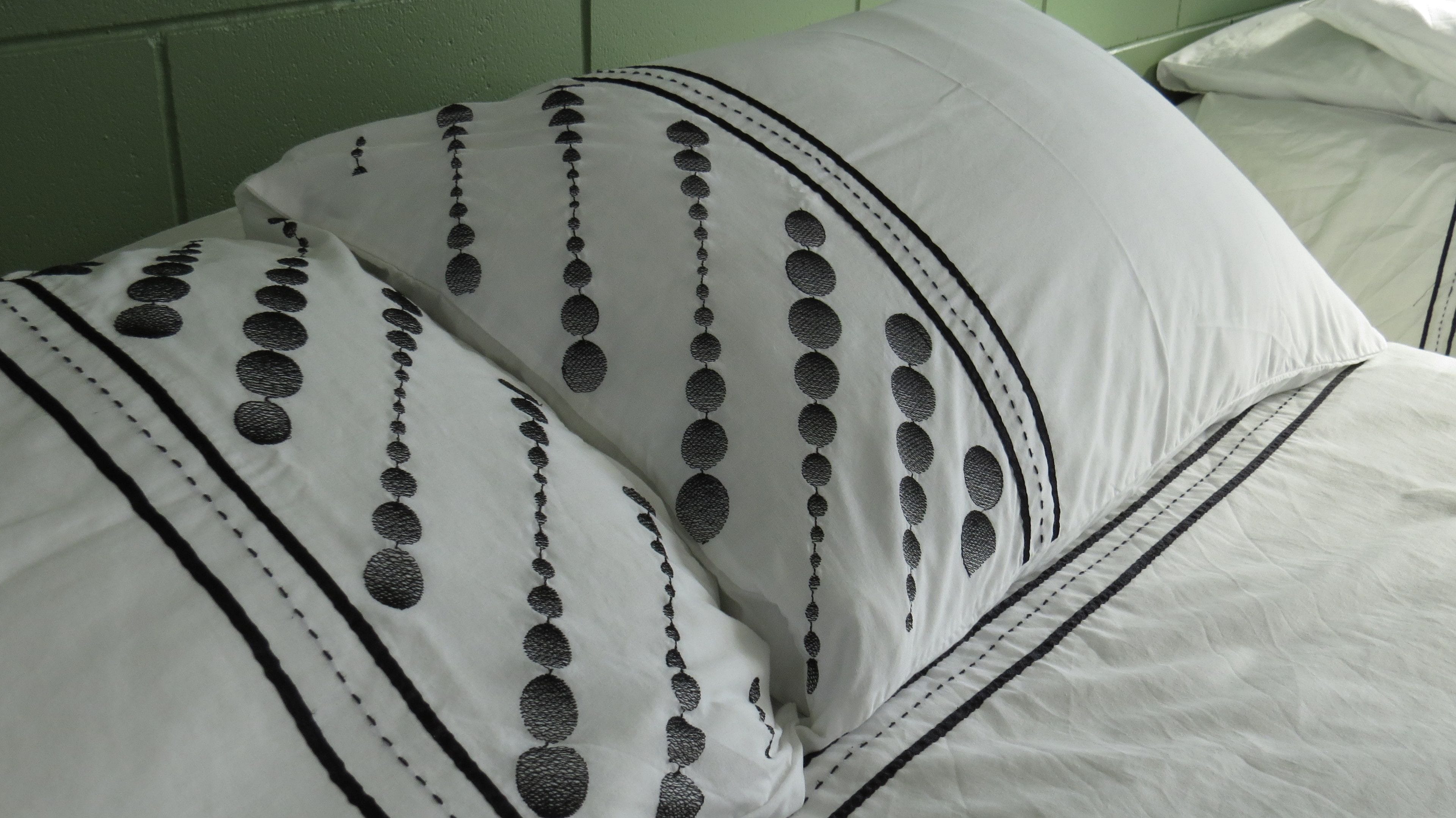 Een bed met wit beddengoed en zwarte cirkelvormige patronen.