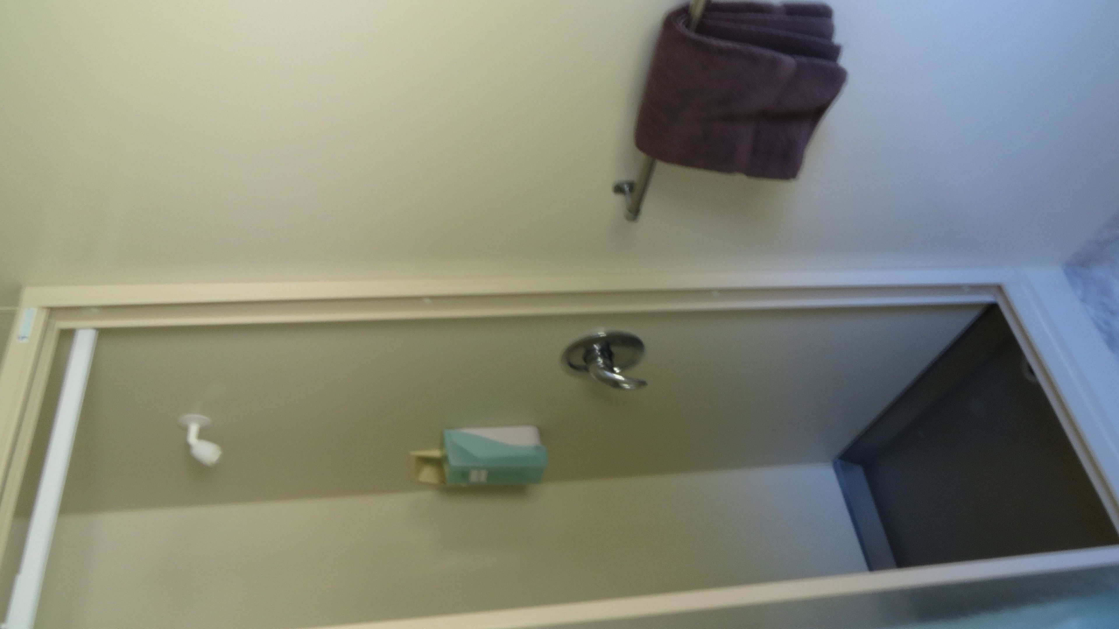 Un baño con una bañera, un perchero para toallas y un dispensador de jabón.