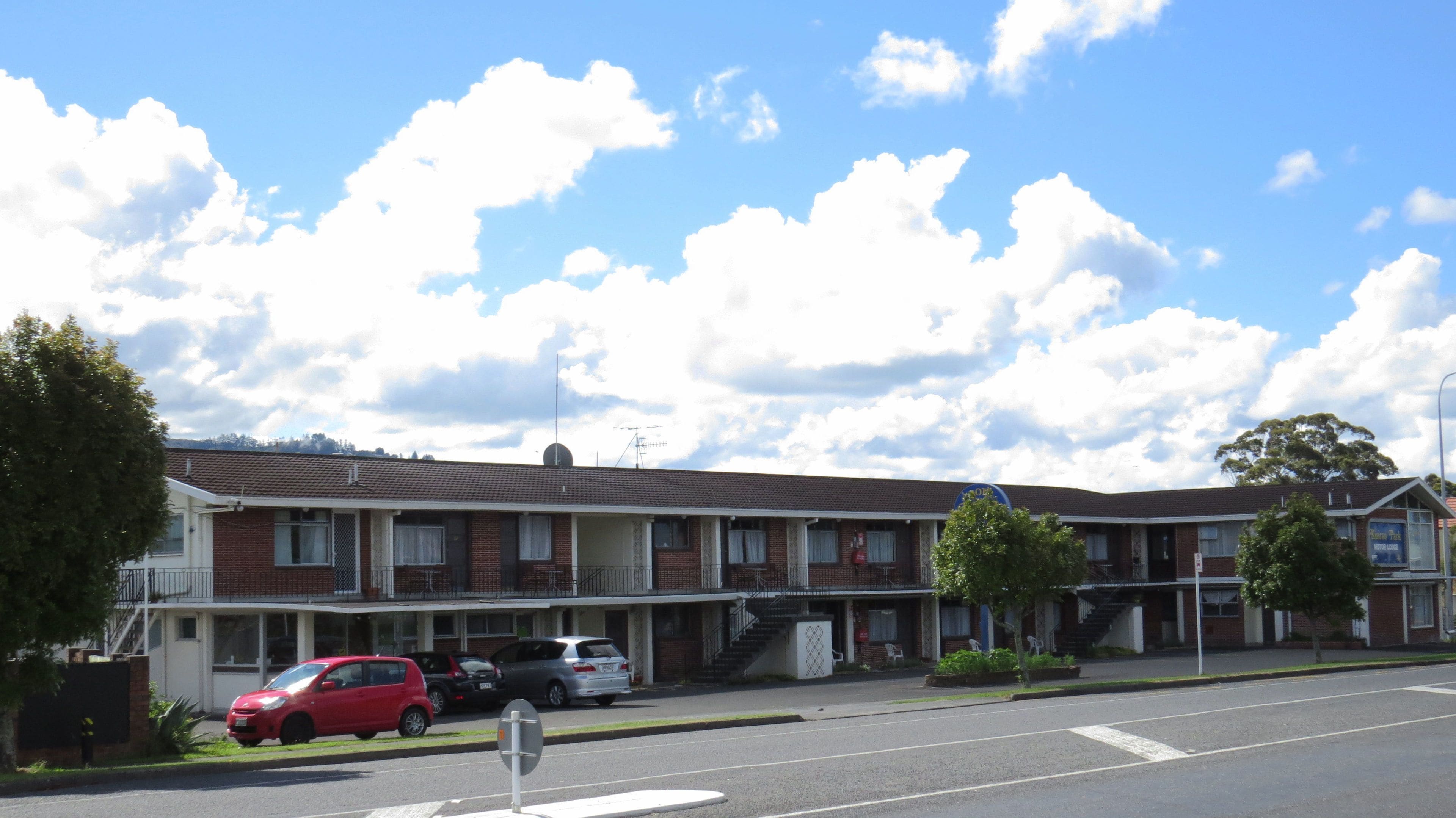 Un motel de dos pisos con fachada de ladrillo, varias ventanas y una escalera visible que conduce al piso superior.