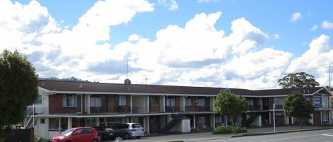 Un motel de dos pisos con fachada de ladrillo, varias ventanas y una escalera visible que conduce al piso superior.