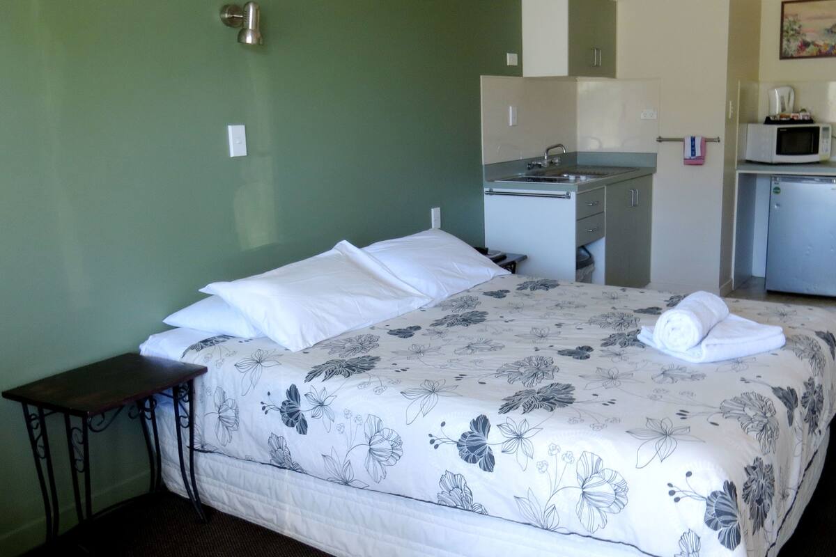 Ein Hotelzimmer mit einem Bett, einem kleinen Schreibtisch, einer Mikrowelle und einem Waschbecken.