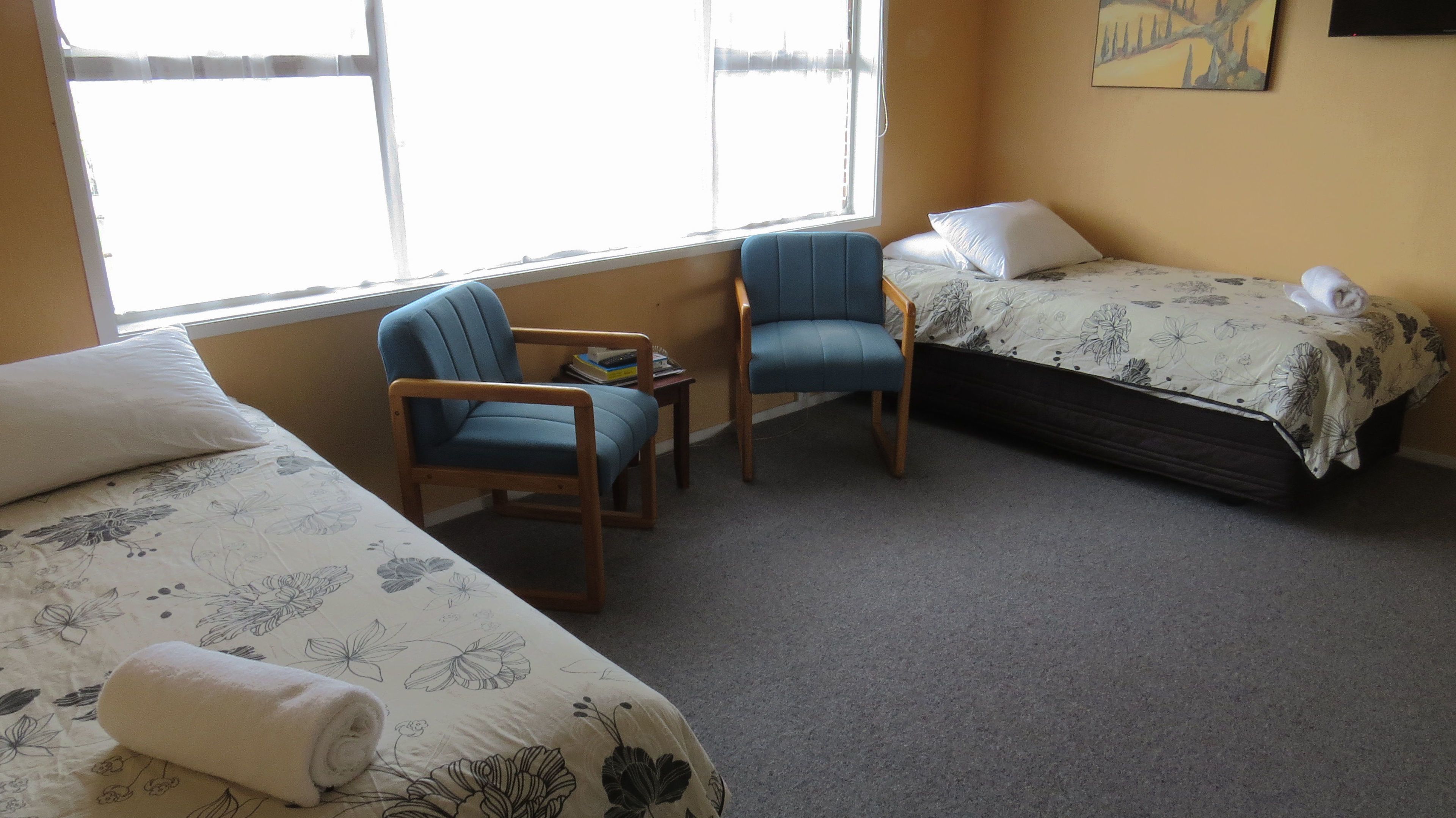 A room with two beds, a small table, two chairs, and a window.