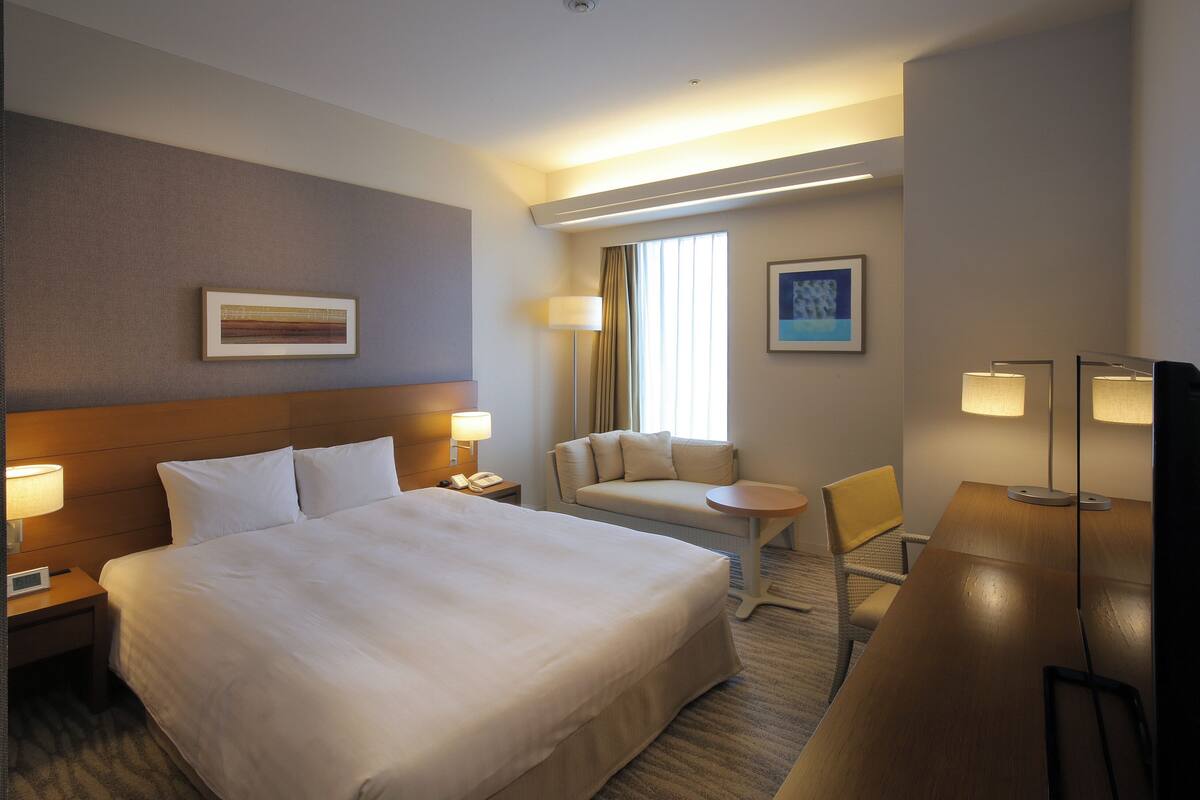 Ein Hotelzimmer mit einem großen Bett, einem Schreibtisch, einem Sessel, einer Couch und zwei Lampen.