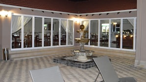 An outdoor patio area with a fountain, seating, and a view of the interior dining area.
