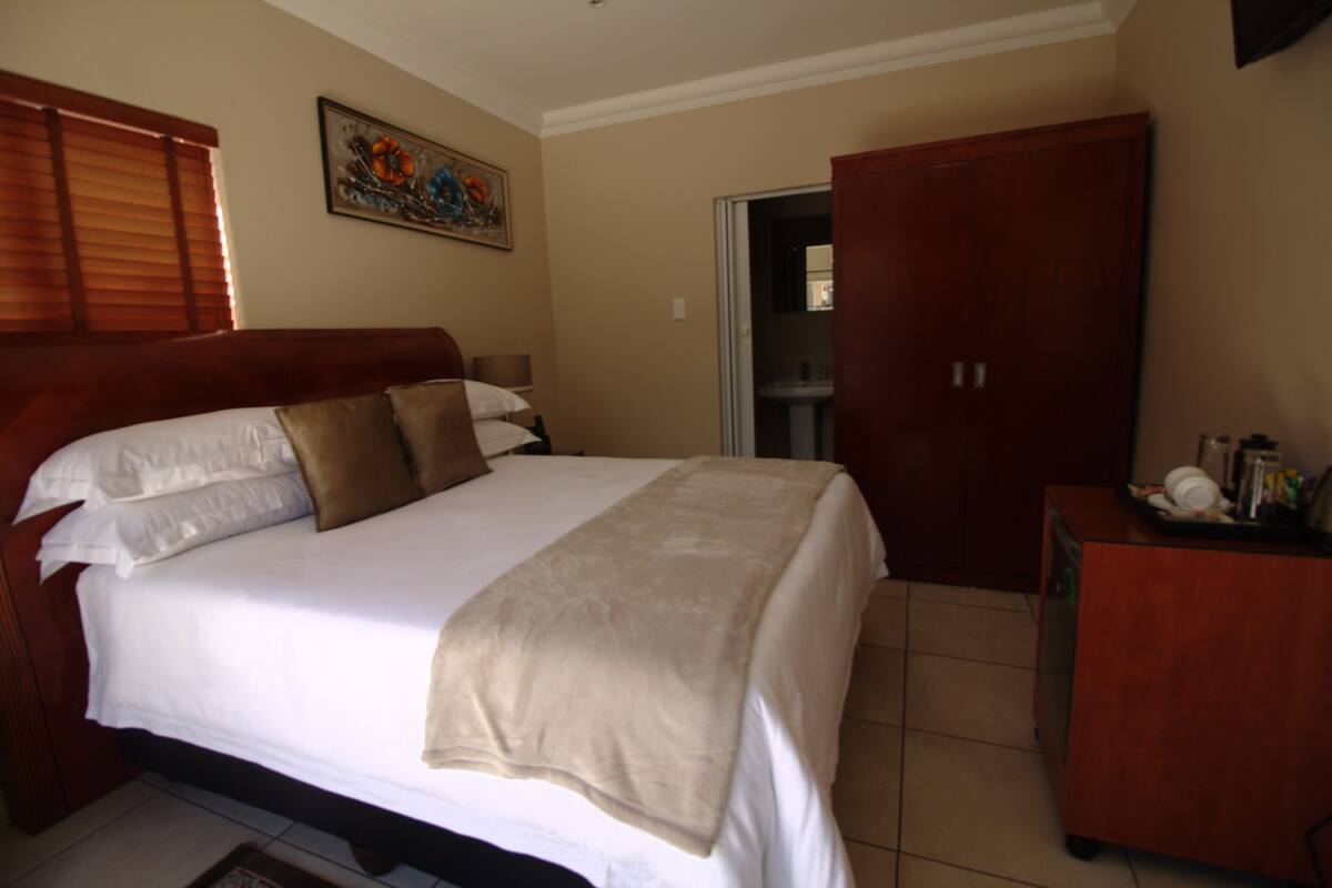 Un dormitorio con cama, armario y un cuadro en la pared.