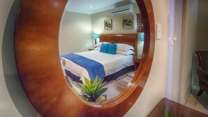 A hotel room with a bed, a nightstand, a lamp, and a potted plant.