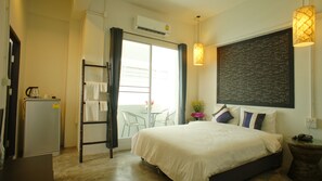 A hotel room with a bed, a desk, a chair, a refrigerator, a window with curtains, and a wall with a chalkboard. - Walking Street Residence (Chiang Mai)