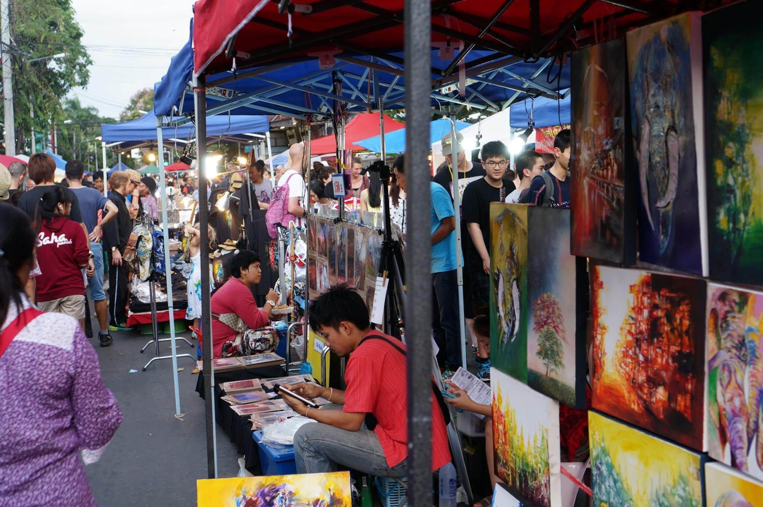 A bustling outdoor market with various stalls and people browsing.