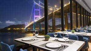 Un restaurante con mesas dispuestas para comer, con vistas a un puente de noche.