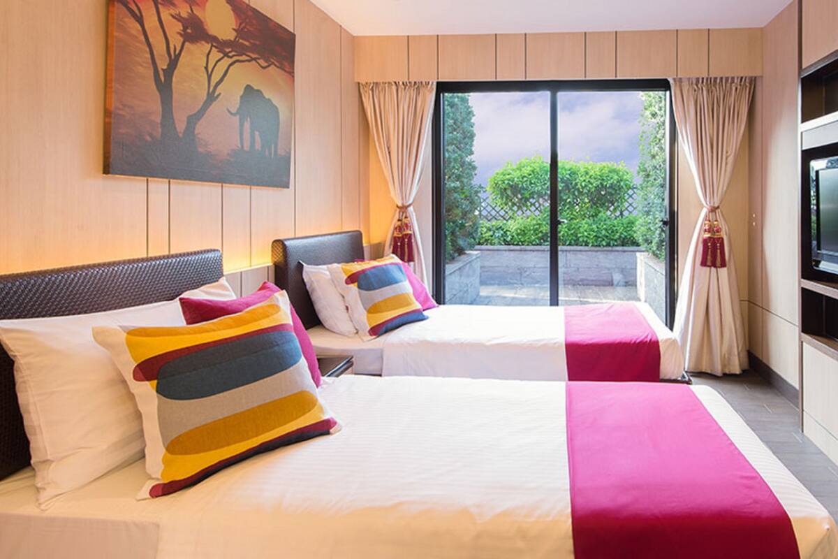 Een hotelkamer met twee bedden, een televisie en een groot raam met gordijnen.