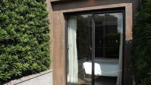 Un dormitorio moderno con un ventanal corredizo, una cama bien tendida y suelo de madera.