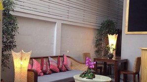 A cozy indoor seating area with a sofa, a round table, and a tall lamp. - La Pillow8 (Chiang Mai)