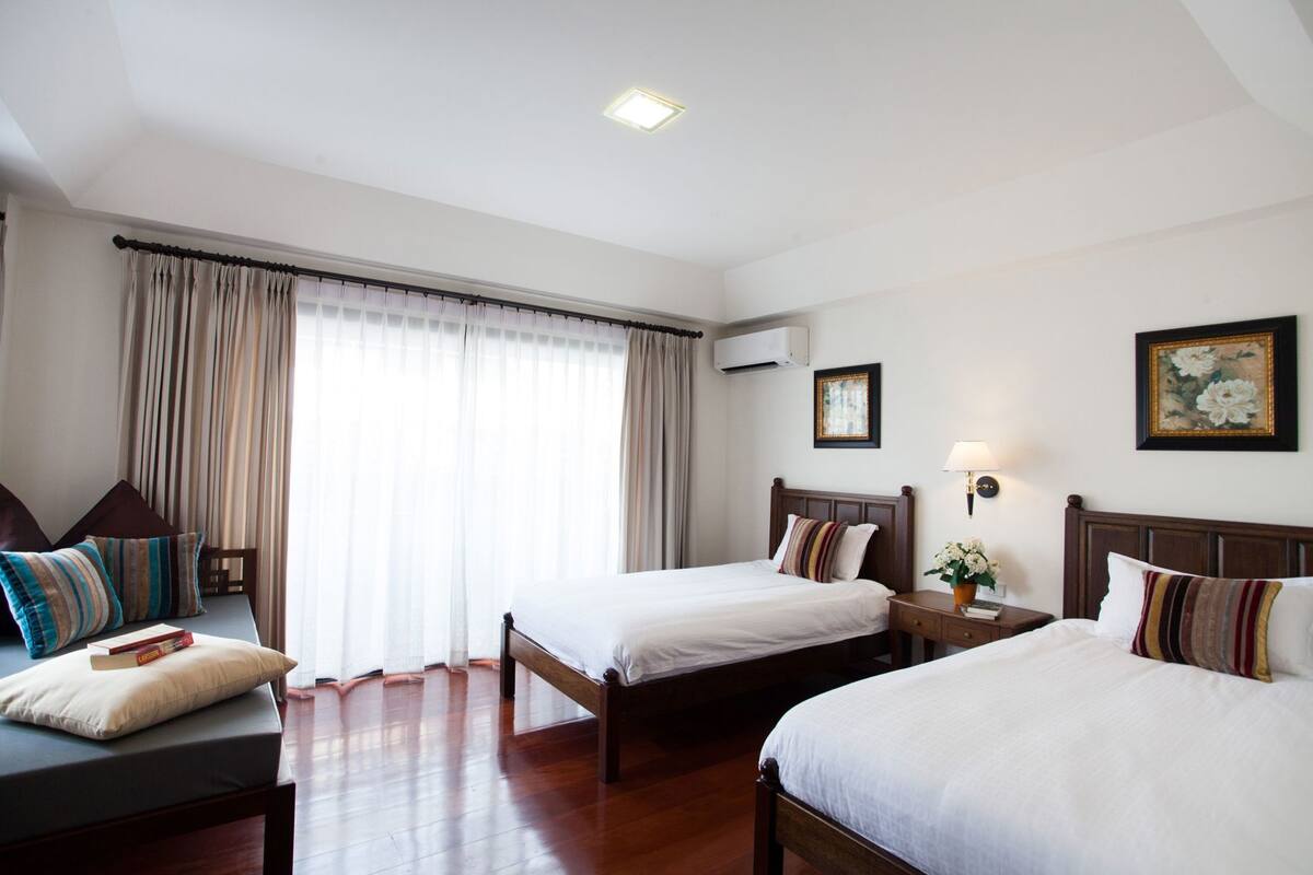 A hotel room with two beds, a desk, a chair, and a window with curtains.