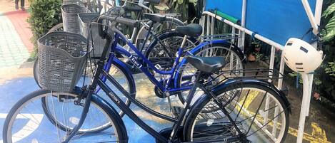 Un vélo bleu, doté d’un panier et d’un casque fixés à un support, est garé sur une surface bleue avec des marquages jaunes.