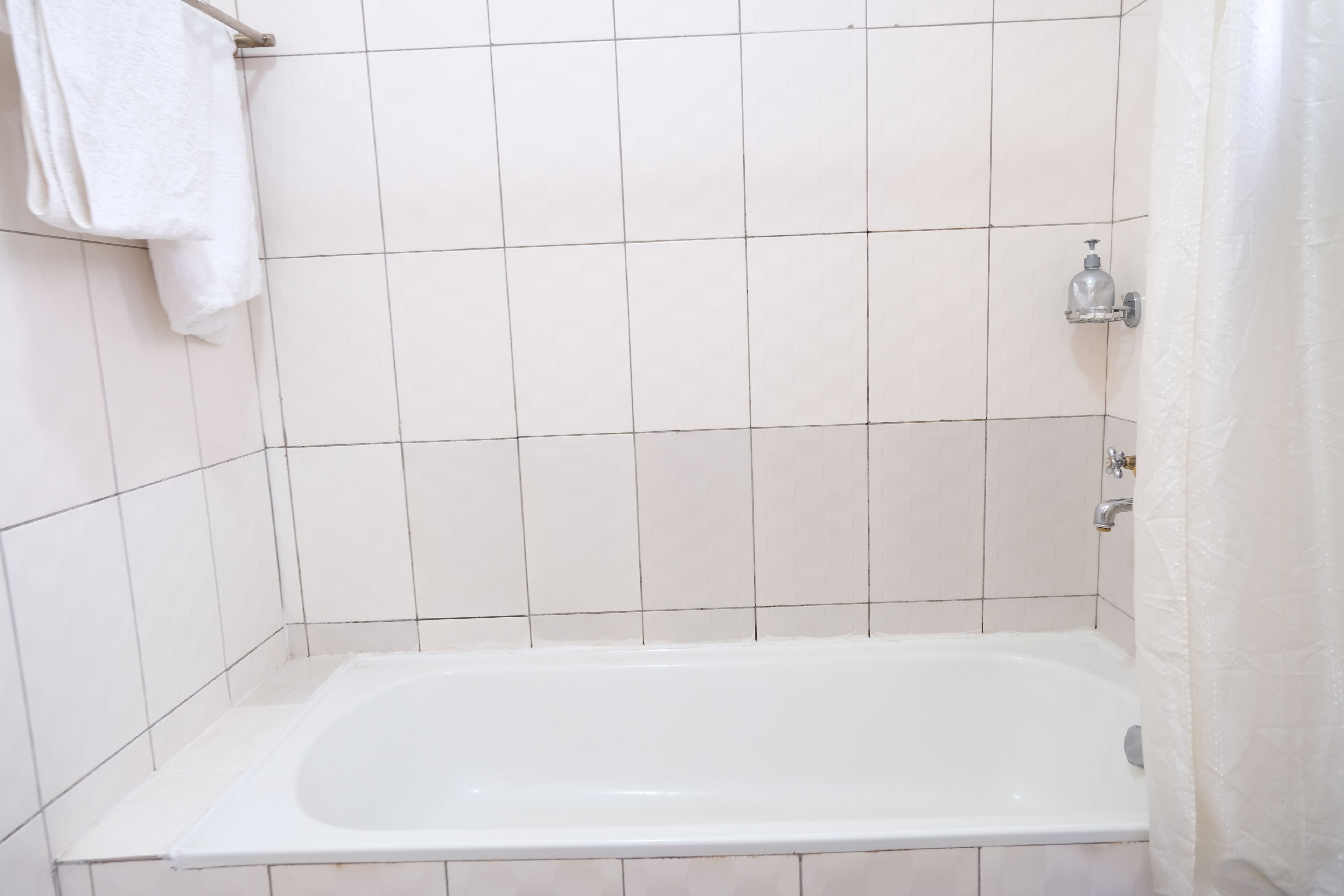 Ein Badezimmer mit einer weißen Badewanne, gefliesten Wänden und einer Duschkabine.