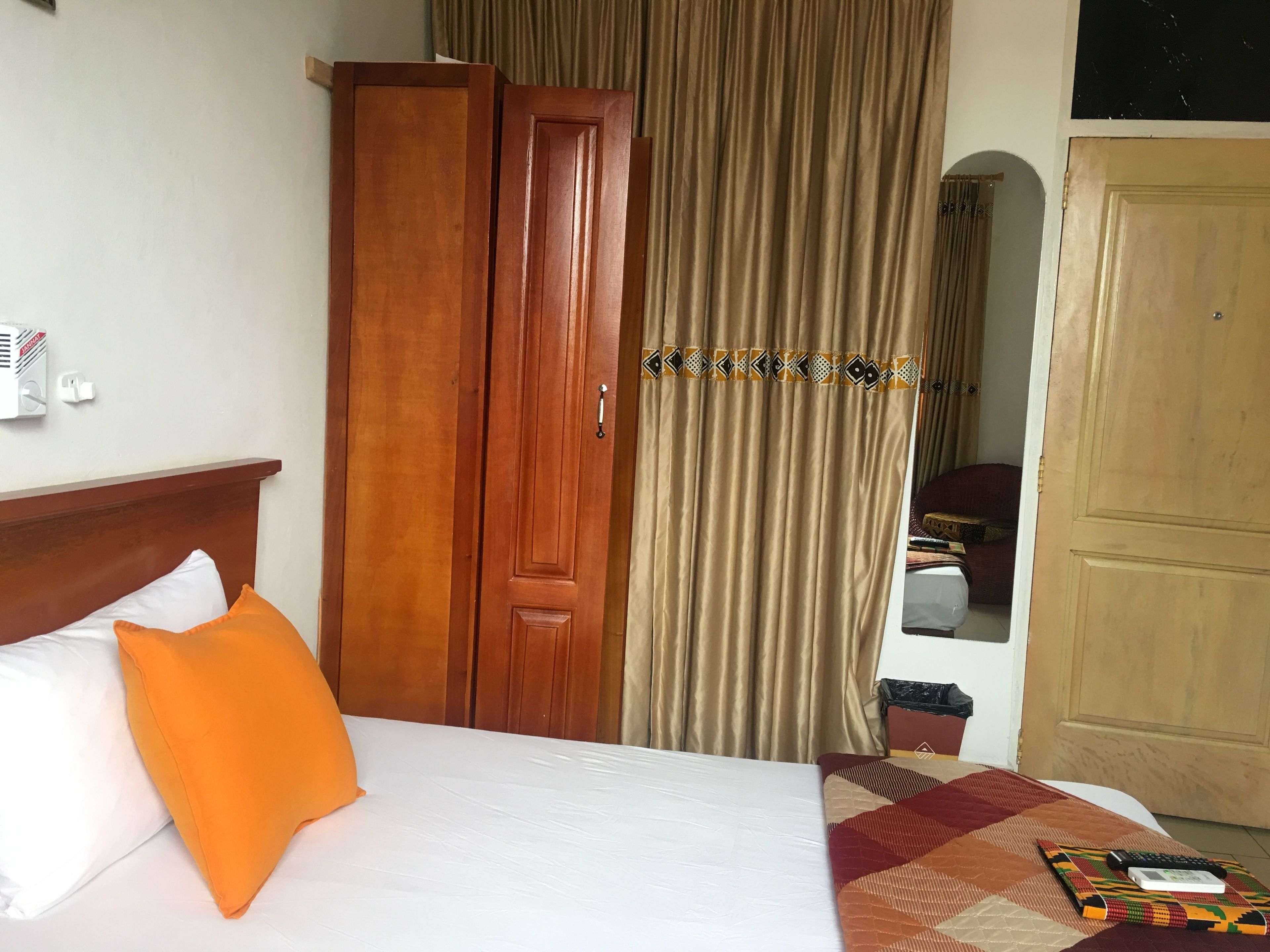 Una habitación de hotel con una cama, un armario, una cortina y una puerta.