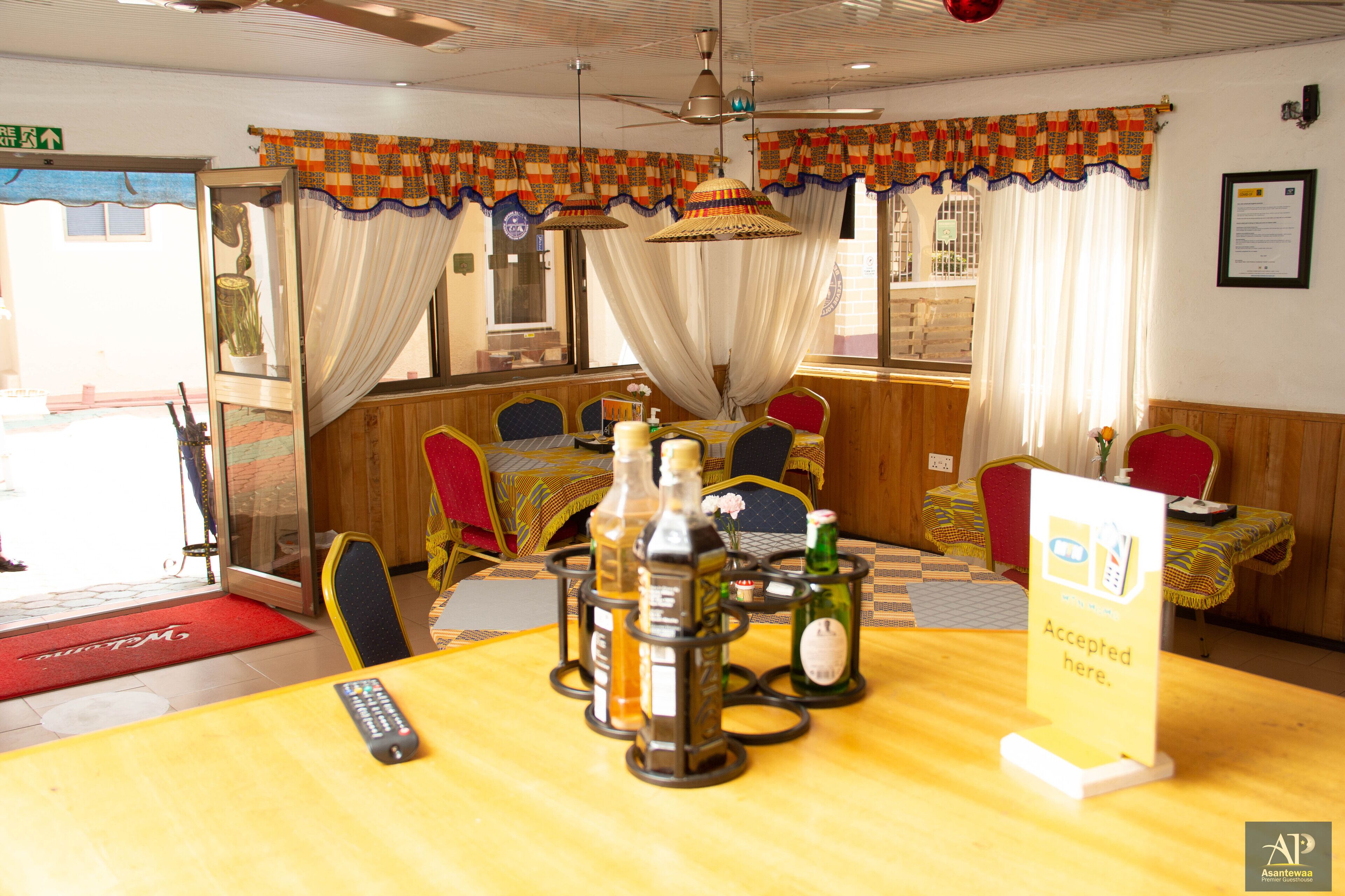 A restaurant with a wooden interior, a central table with bottles, and a sign indicating acceptance of credit cards.