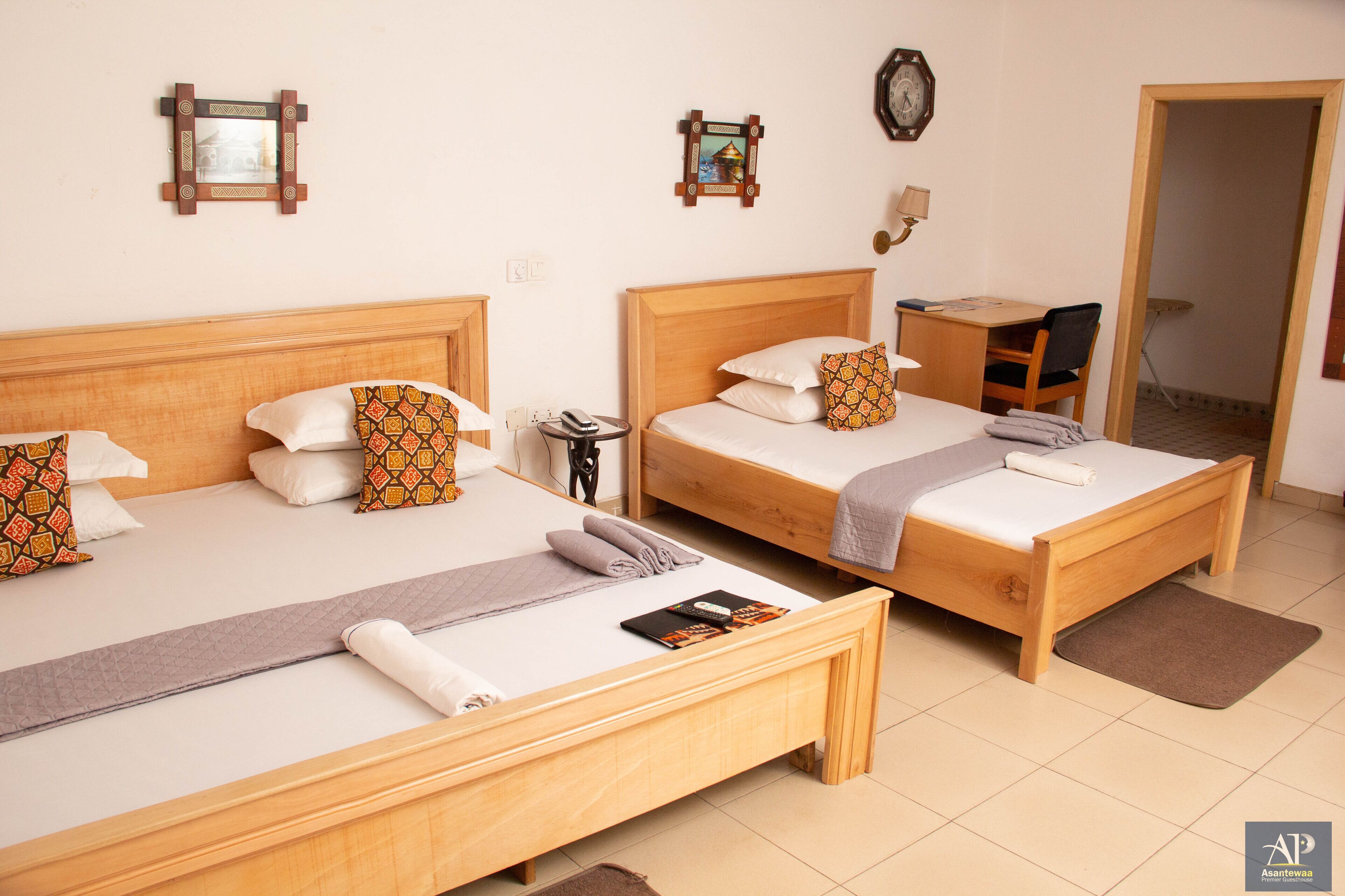 A hotel room with two wooden beds, a desk, and a chair.