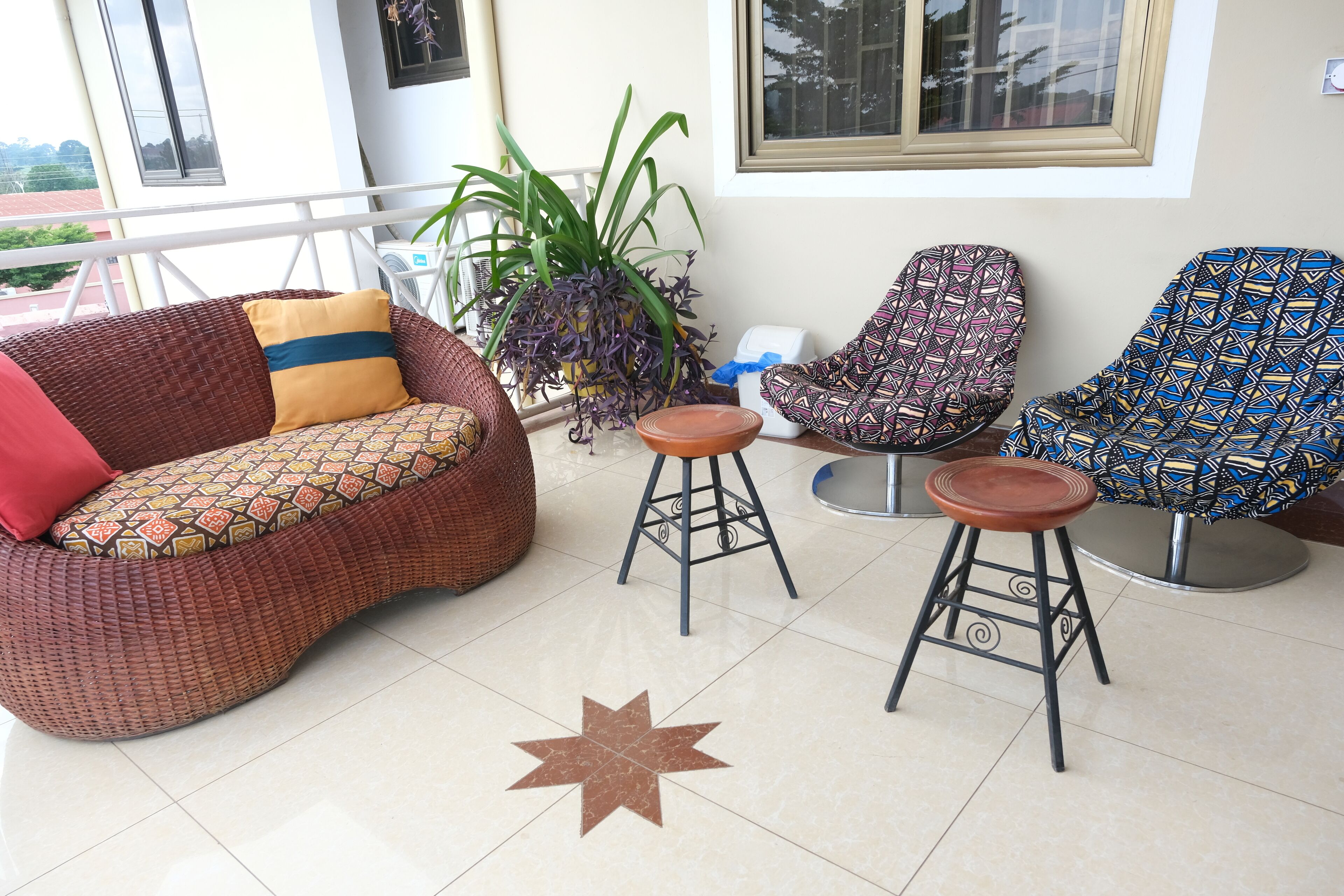 Un área de estar moderna con un sofá estampado, dos taburetes de bar y una planta en maceta.