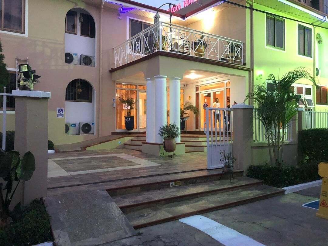 A hotel entrance with a double staircase, a balcony, and a gated entrance.