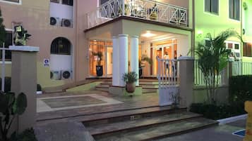 A hotel entrance with a double staircase, a balcony, and a gated entrance.